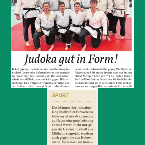 Gruppenfoto von Judokas in weißen und schwarzen Judogis auf einer Matte, lächeln und posieren gemeinsam.