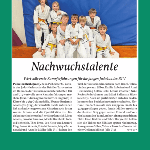 Gruppenfoto von jungen Judokas in weißen Anzügen mit orangen Gürteln, sitzend vor blauer Judowand.
