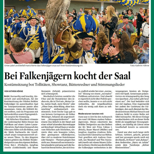Kostümiertes Falkenjägercorps marschiert feiernd in einem Saal, umgeben von applaudierenden Gästen und bunten Ballons.