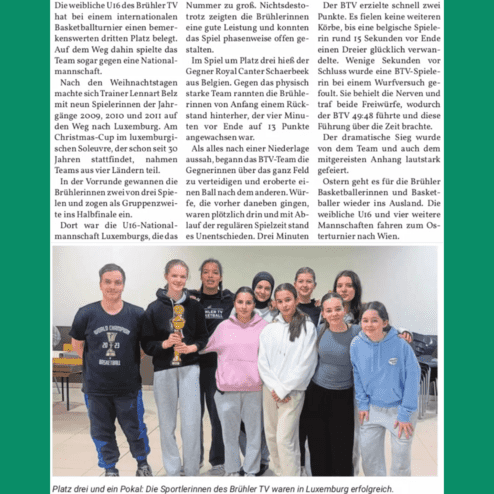 Zehn Basketballspielerinnen des Brühler TV stehen lächelnd mit einem Pokal in einem Raum.