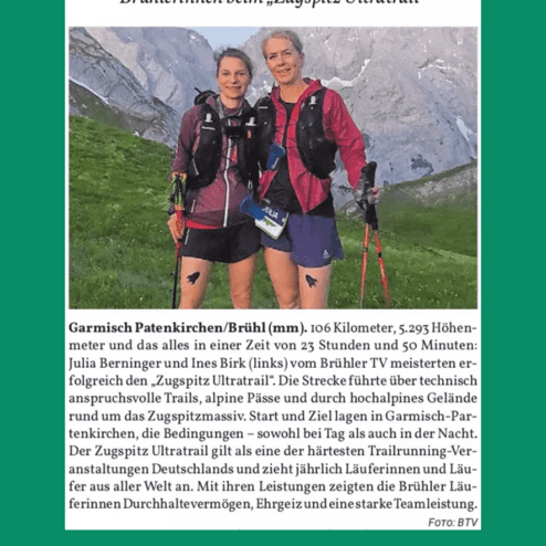 Zwei Frauen in Sportbekleidung stehen lächelnd vor einer Berglandschaft nach dem Zugspitz Ultratrail.
