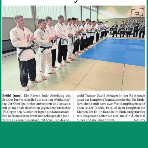 Gruppenszene von Judokas in weißen Anzügen, die auf einer Matte stehen und applaudieren.