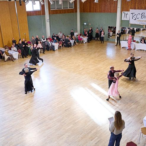 Tanzveranstaltung im TSC Brühl mit mehreren Paaren, die auf einer Holzfläche tanzen, umgeben von Zuschauern.
