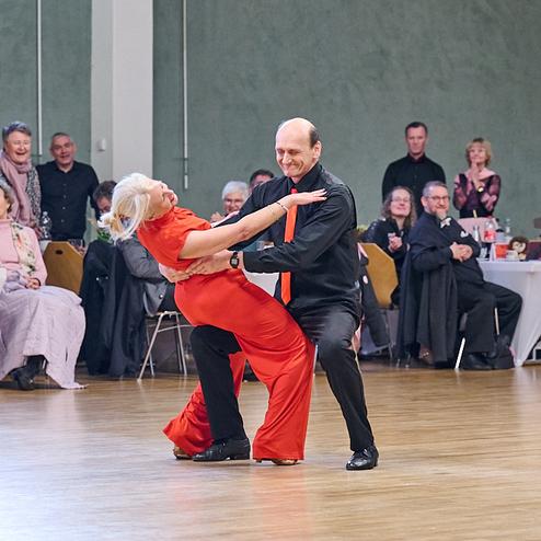 Tanzpaar führt einen leidenschaftlichen Tanz auf einer Veranstaltung, umgeben von applaudierendem Publikum.