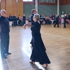 Tanzpaar in Abendgarderobe, das sich auf einer Tanzfl&auml;che gegen&uuml;bersteht, umgeben von Publikum.
