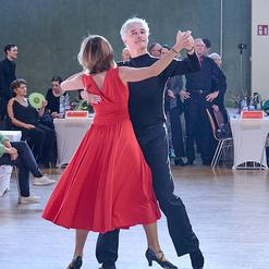 Tanzpaar in eleganter Kleidung f&uuml;hrt einen Schritt im Wettbewerb auf einer Tanzfl&auml;che vor Publikum.