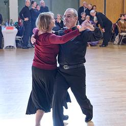 Tanzendes Paar in eleganter Kleidung auf einer Tanzfl&auml;che, umgeben von Zuschauern.