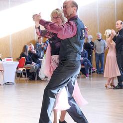 Tanzpaar in eleganter Kleidung tanzt leidenschaftlich in einem hellen Saal w&auml;hrend eines Wettbewerbs.