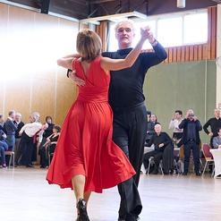 Tanzpaar in eleganter Pose auf einer Tanzfl&auml;che, umgeben von Zuschauern in einem festlichen Ambiente.