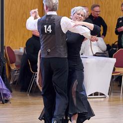 Tanzendes Paar auf einer Tanzfl&auml;che, der Mann tr&auml;gt eine Nummer 14 auf seinem R&uuml;cken, die Frau l&auml;chelt.