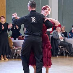 Tanzende Paare in eleganter Kleidung auf einer Tanzfl&auml;che w&auml;hrend eines Wettbewerbs, Zuschauer im Hintergrund.