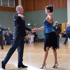 Tanzpaar in eleganter Kleidung vollzieht eine Figurenkombination auf einer Tanzfl&auml;che w&auml;hrend eines Wettbewerbs.