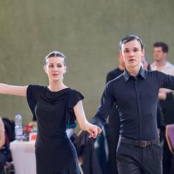 Tanzpaar in eleganter Kleidung, das auf einer Tanzfl&auml;che eine Darbietung pr&auml;sentiert, im Hintergrund Zuschauer.