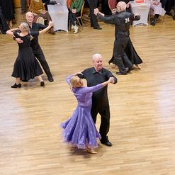 Tanzpaar f&uuml;hrt einen Walzer in eleganter Kleidung auf einem Holzparkettboden bei einer Tanzveranstaltung aus.