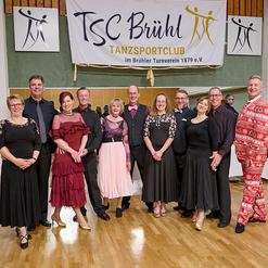 Gruppierung von T&auml;nzern in eleganter Abendkleidung vor Banner des TSC Br&uuml;hl im Tanzsportclub.