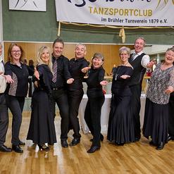 Gruppennahaufnahme von tanzbegeisterten Personen in eleganter Tanzkleidung, die freundlich in die Kamera l&auml;cheln.