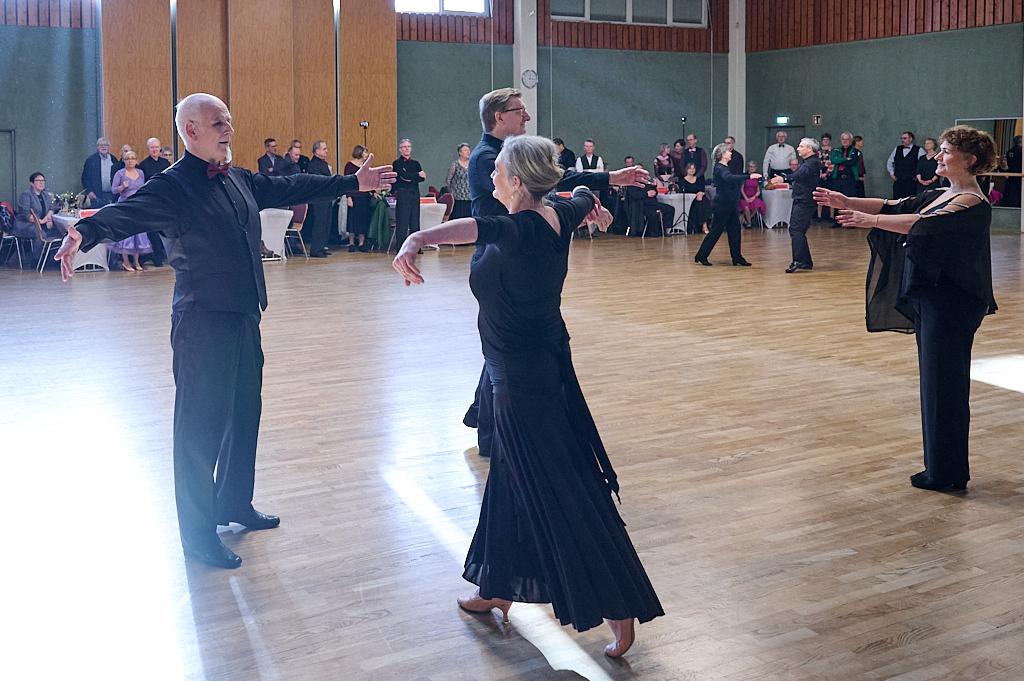 Tanzpaar in Abendgarderobe, das sich auf einer Tanzfl&auml;che gegen&uuml;bersteht, umgeben von Publikum.