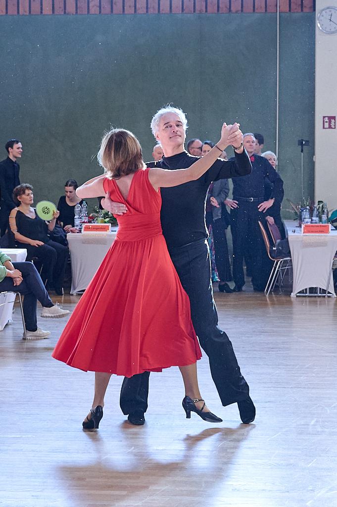 Tanzpaar in eleganter Kleidung f&uuml;hrt einen Schritt im Wettbewerb auf einer Tanzfl&auml;che vor Publikum.