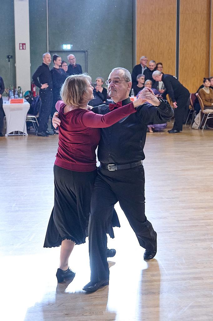 Tanzendes Paar in eleganter Kleidung auf einer Tanzfl&auml;che, umgeben von Zuschauern.