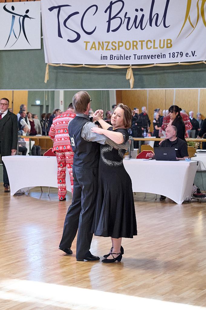 Tanzpaar in eleganter Kleidung tanzt auf einer Sportveranstaltung, im Hintergrund Zuschauer und ein Banner des TSC Br&uuml;hl.