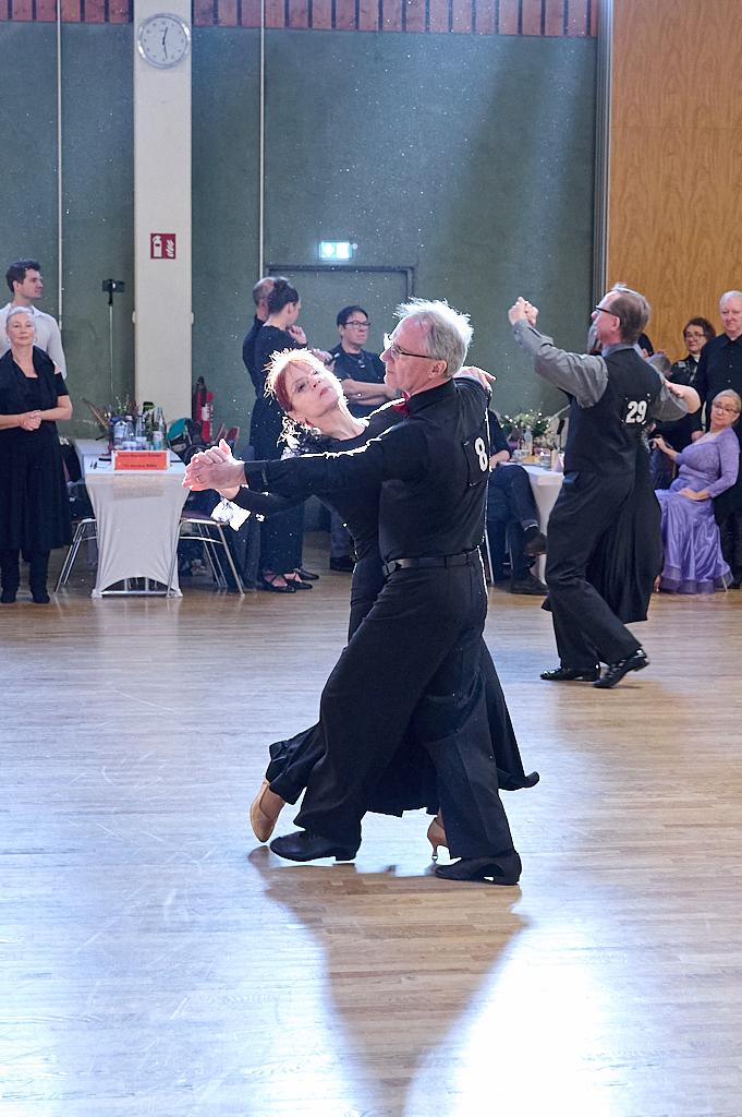 Tanzpaar in eleganter Kleidung f&uuml;hrt einen Walzer auf einer Tanzfl&auml;che vor Publikum aus.
