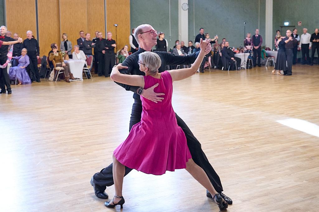 Tanzpaar in eleganter Tanzpose auf einer Holzfl&auml;che vor Publikum bei einer Tanzveranstaltung.