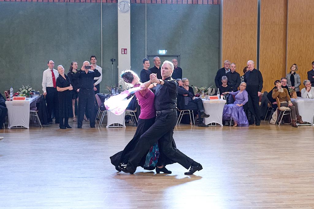 Tanzpaar in eleganter Kleidung f&uuml;hrt eine anspruchsvolle Choreografie auf einer Tanzfl&auml;che vor Publikum auf.