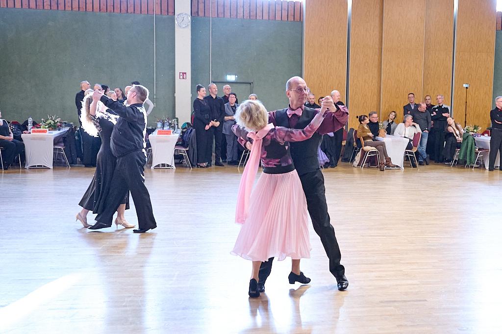 Paare tanzen auf einer Tanzfl&auml;che, im Hintergrund Zuschauer an Tischen bei einer Tanzveranstaltung.