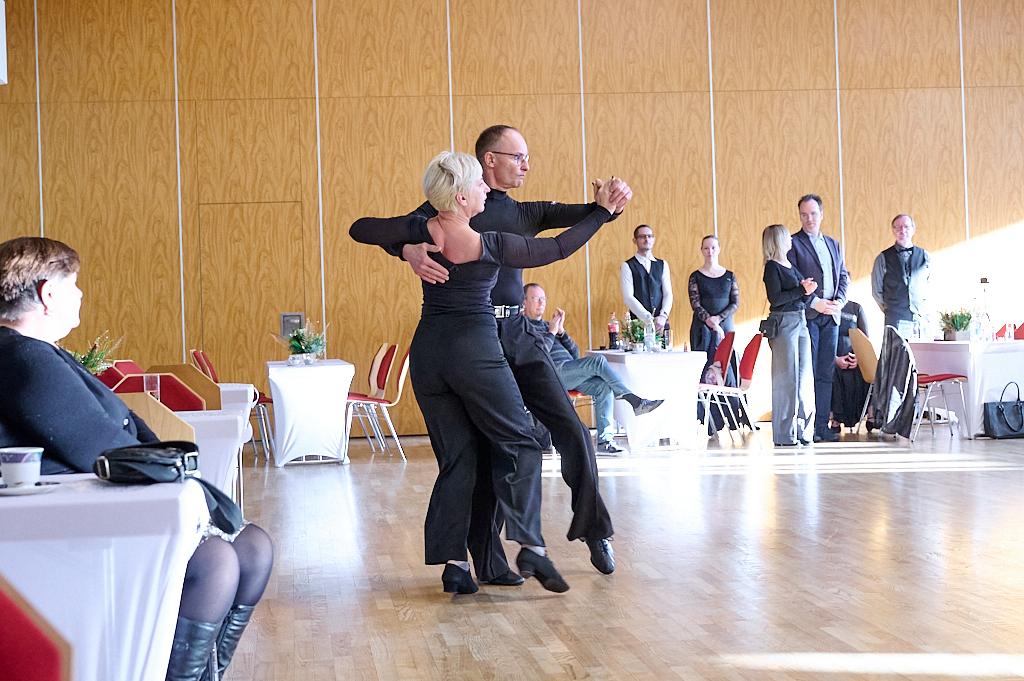 Tanzpaar in eleganter Kleidung, das auf einer Tanzfl&auml;che in einem Saal zu sehen ist, w&auml;hrend Zuschauer beobachten.