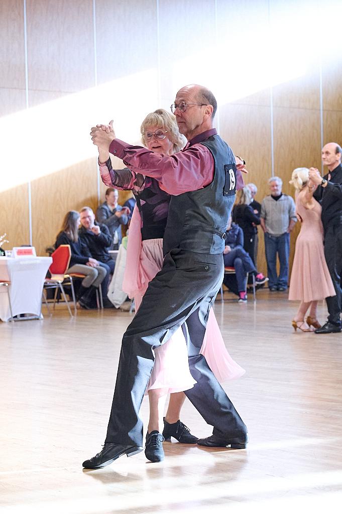 Tanzpaar in eleganter Kleidung tanzt leidenschaftlich in einem hellen Saal w&auml;hrend eines Wettbewerbs.