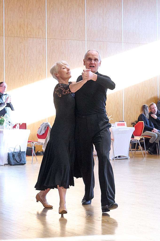 &Auml;lteres Paar tanzt miteinander in eleganter Kleidung auf einer lichtdurchfluteten Tanzfl&auml;che.