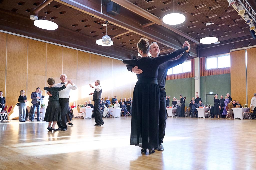 Paare tanzen in eleganter Kleidung auf einer Tanzfl&auml;che in einem festlich dekorierten Saal.