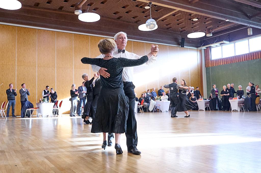 Tanzende Paare in eleganter Kleidung auf einer Tanzfl&auml;che in einem festlich dekorierten Raum. Publikum applaudiert.