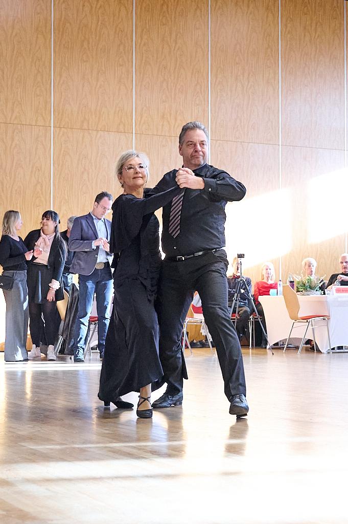 Tanzendes Paar in eleganter Kleidung auf einer Tanzfl&auml;che, im Hintergrund Zuschauer bei einer Veranstaltung.