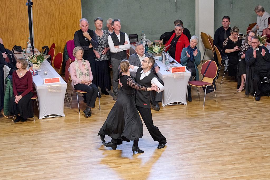Tanzpaar in eleganter Kleidung tanzt auf einer Veranstaltung, w&auml;hrend das Publikum applaudiert und zuschaut.
