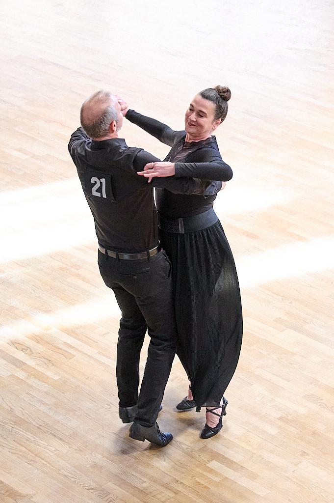 Tanzpaar in eleganter Kleidung tanzt auf einem Holzfu&szlig;boden, der helle Raum wird von nat&uuml;rlichem Licht erhellt.