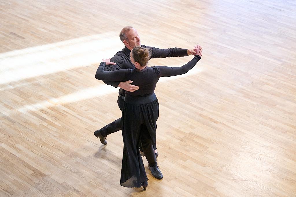 Tanzendes Paar in eleganter Kleidung auf einem Holzfu&szlig;boden; sie stehen eng umschlungen in einer Tanzpose.