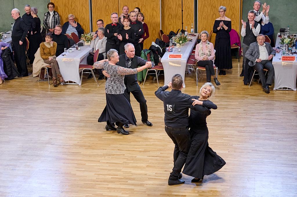 Tanzpaar in eleganter Kleidung f&uuml;hrt einen Walztanz auf einer Holz-Tanzfl&auml;che vor Publikum auf.