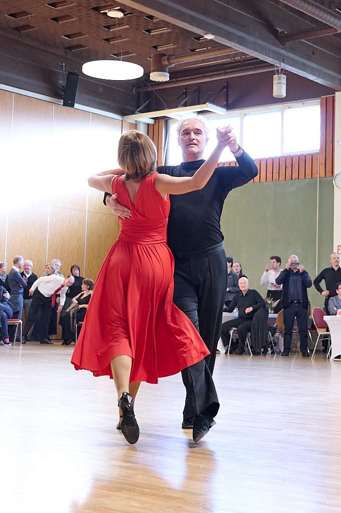 Tanzpaar in eleganter Pose auf einer Tanzfl&auml;che, umgeben von Zuschauern in einem festlichen Ambiente.