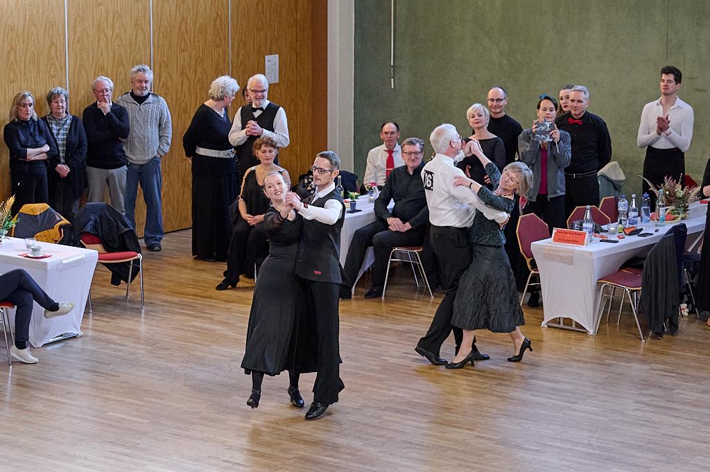 Tanzpaare treten bei einem Wettbewerb in einem festlich dekorierten Saal auf, w&auml;hrend Zuschauer applaudieren.