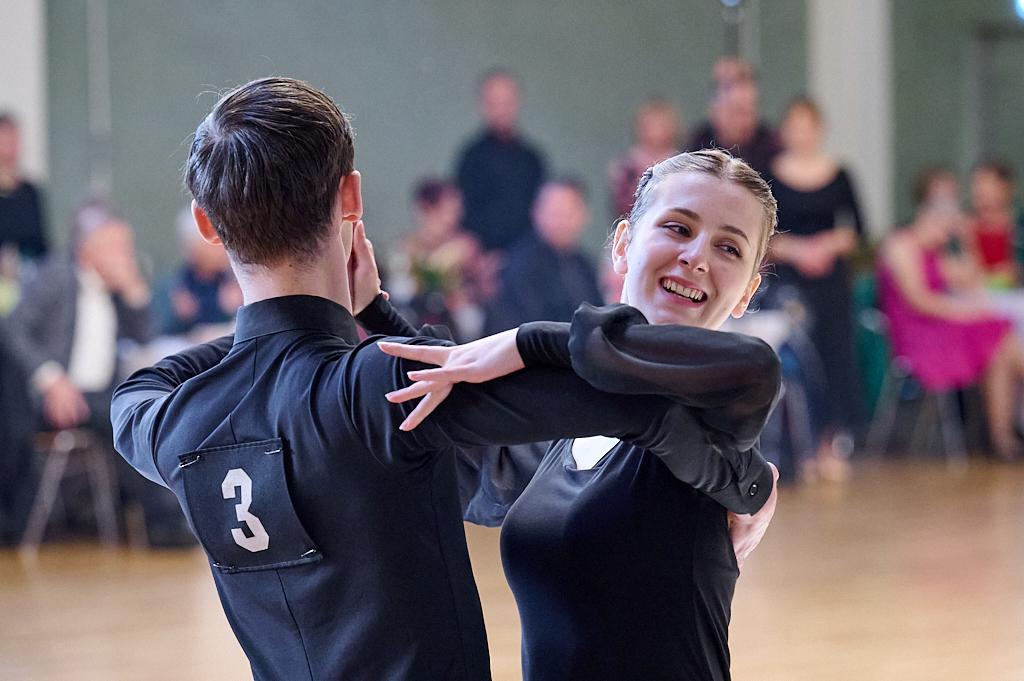 Tanzpaar in eleganter Kleidung w&auml;hrend eines Wettbewerbs, l&auml;chelnd und in einer t&auml;nzerischen Pose auf der Fl&auml;che.