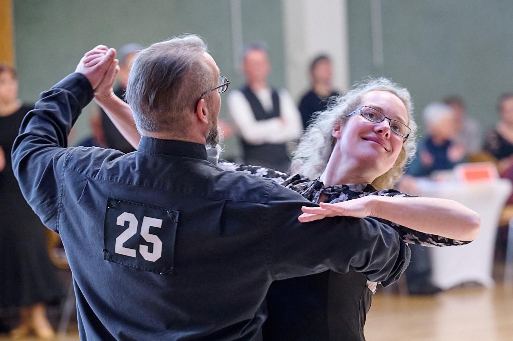 T&auml;nzerisches Paar in eleganter Kleidung bei einem Tanzwettbewerb, Nummer 25 auf dem R&uuml;cken des Mannes sichtbar.