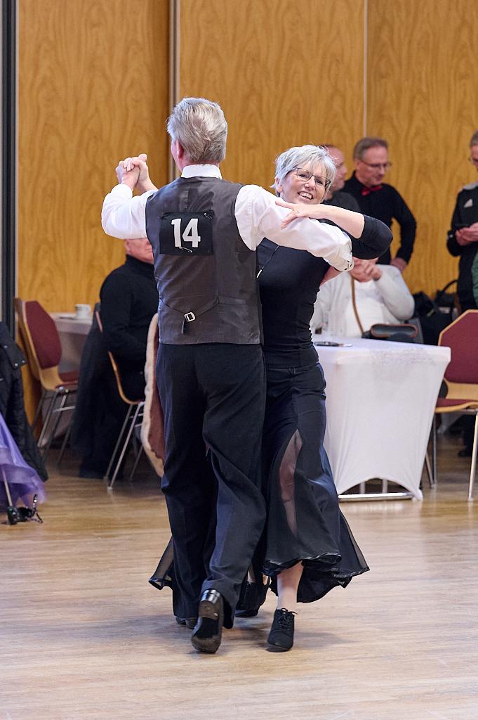Tanzendes Paar auf einer Tanzfl&auml;che, der Mann tr&auml;gt eine Nummer 14 auf seinem R&uuml;cken, die Frau l&auml;chelt.