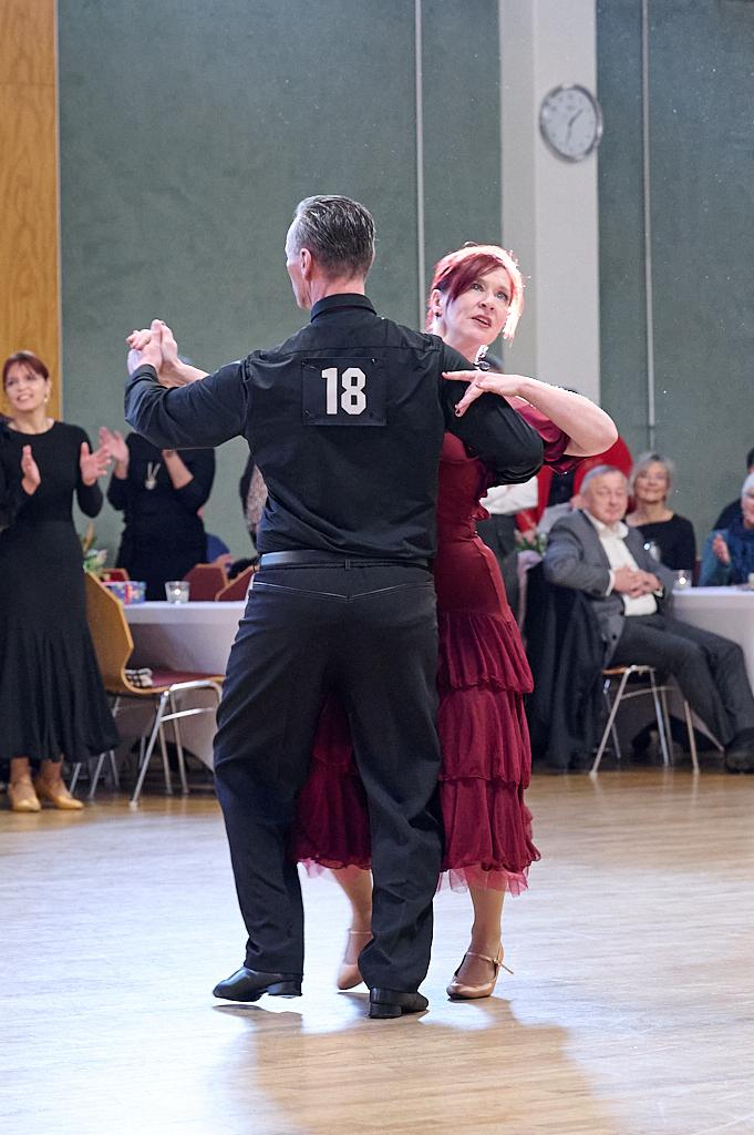 Tanzende Paare in eleganter Kleidung auf einer Tanzfl&auml;che w&auml;hrend eines Wettbewerbs, Zuschauer im Hintergrund.