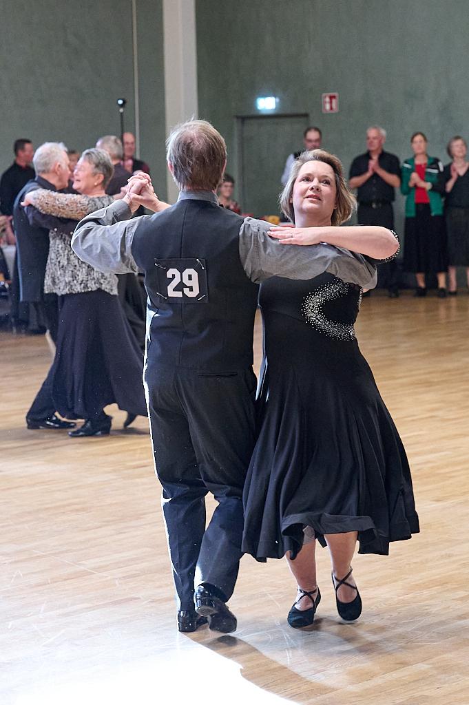 Tanzpaar in eleganter Kleidung bewegt sich zur Musik auf einer Tanzfl&auml;che, im Hintergrund applaudierende Zuschauer.
