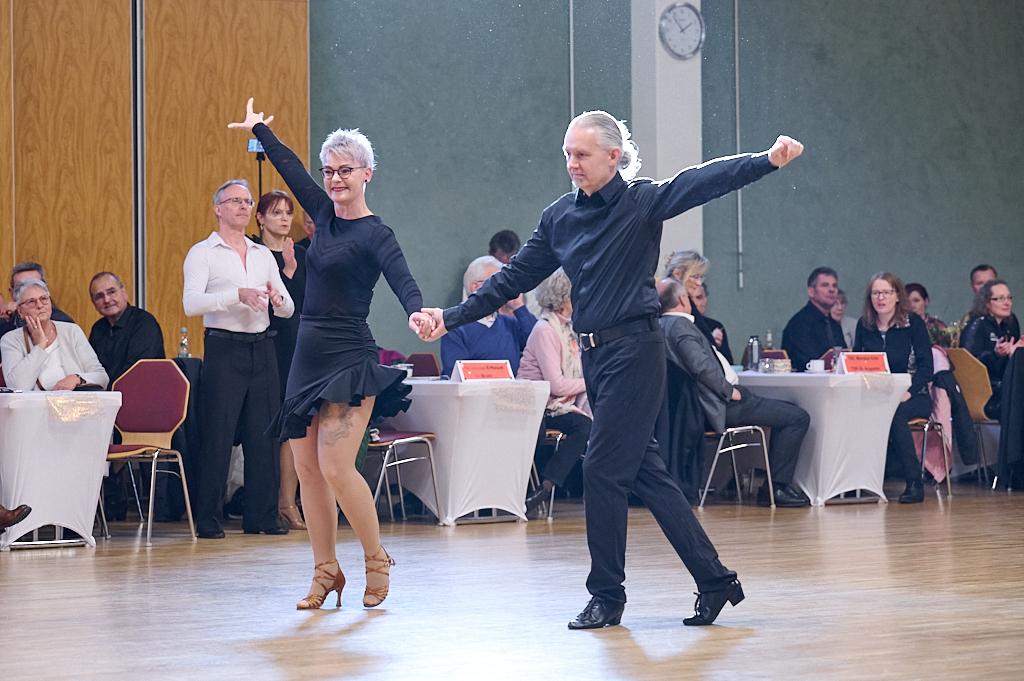 Tanzpaar in eleganter Kleidung zeigt einen Tanz auf einer Veranstaltung, Zuschauer schauen aufmerksam zu.