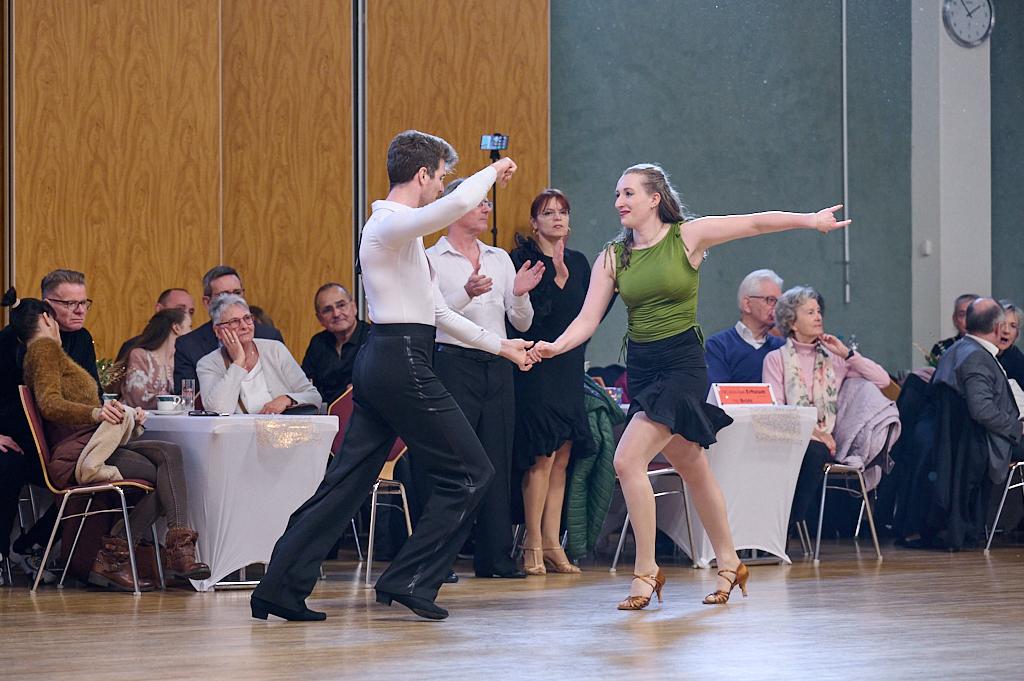 Tanzpaar in eleganter Kleidung beim Tanzwettbewerb, Zuschauer im Hintergrund applaudieren.