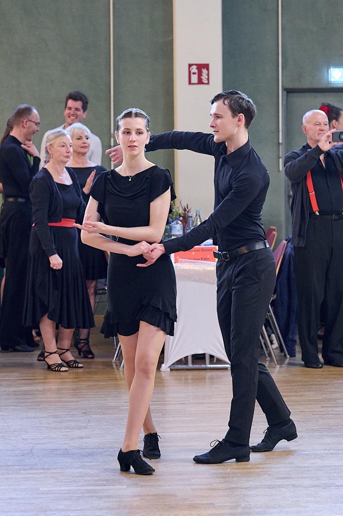 Tanzpaar in eleganter Kleidung f&uuml;hrt eine Tanzhaltung in einer festlichen Umgebung aus, im Hintergrund Zuschauer.