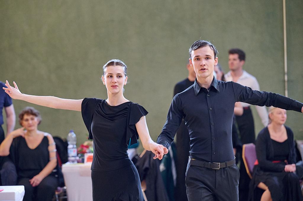 Tanzpaar in eleganter Kleidung, das auf einer Tanzfl&auml;che eine Darbietung pr&auml;sentiert, im Hintergrund Zuschauer.