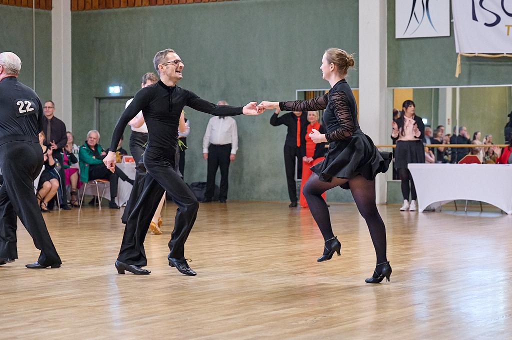 Tanzpaar in eleganter Kleidung zeigt dynamischen Tanz auf einer Holzfl&auml;che w&auml;hrend des Wettbewerbs.